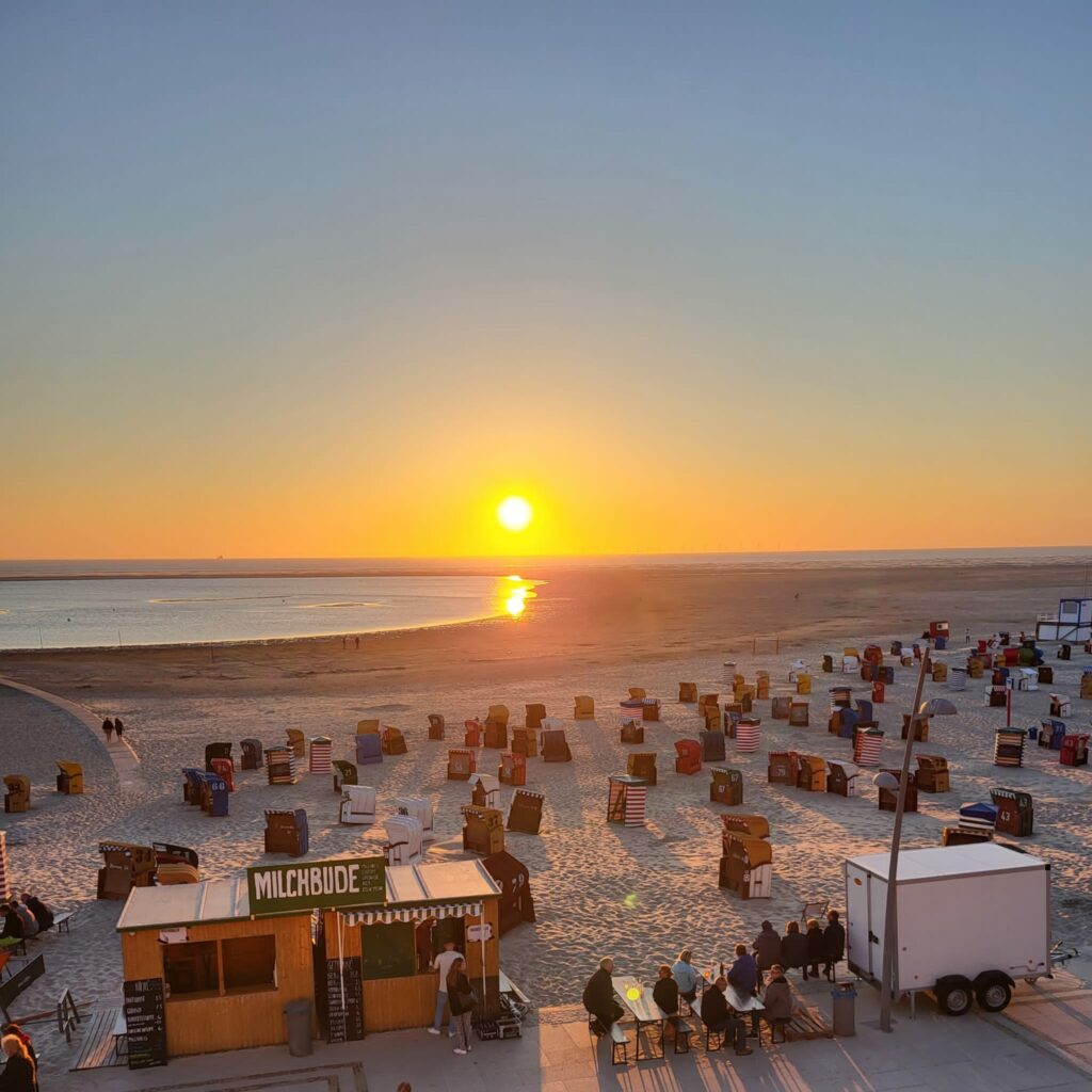 Der Nordstrand von Borkum mit Menschen und Strandkörben bei Sonnenuntergang am 10. Juni 2023.